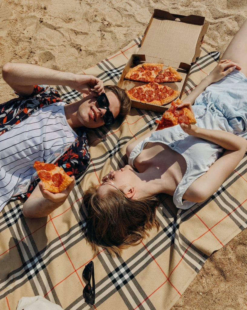 couple eating pizza on beach